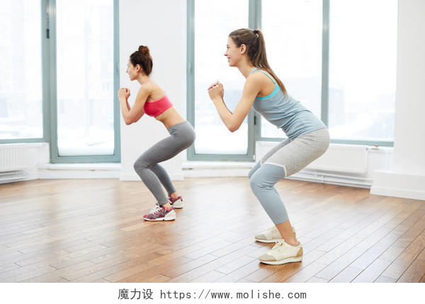 侧视图肖像两个开朗的年轻女子在宽敞的健身工作室工作瑜伽普拉提